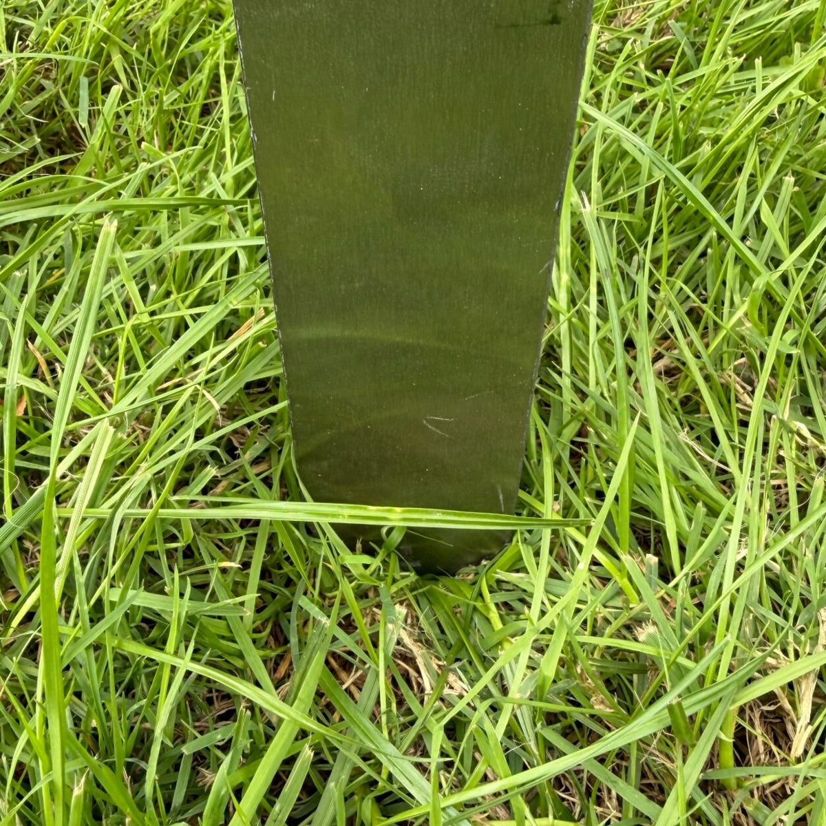 Nahaufnahme des Edelstahl-Erdspießes einer Gedenktafel, im Gras in den Boden gesteckt