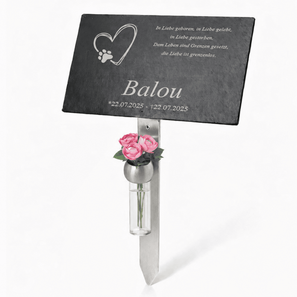 Schwarze Gedenktafel für Balou auf einem Edelstahl-Erdspieß mit kleiner Glasvase und rosa Blumen. Auf der Tafel sind ein Herz mit Pfotenabdruck, ein vierzeiliger deutscher Gedenkspruch sowie der Name „Balou“ und die Lebensdaten eingraviert.