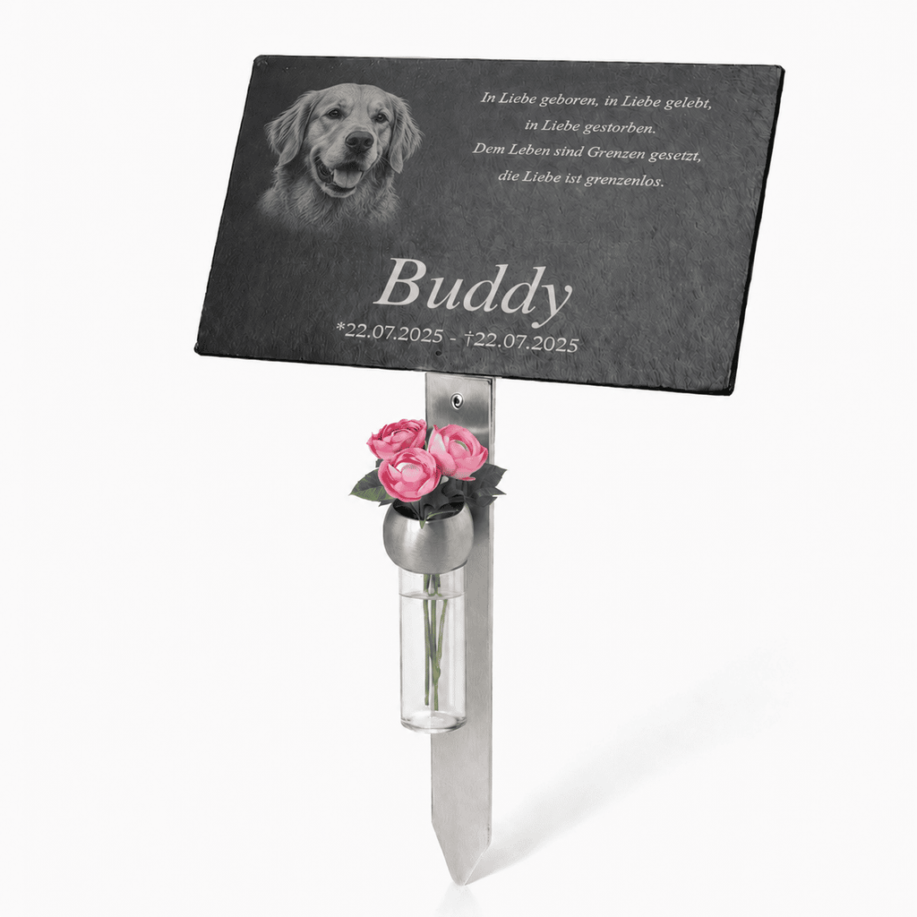 Personalisierter Hunde-Grabstein mit schwarzer rechteckiger Gedenktafel. Darauf sind das Porträt eines Golden Retrievers, der Name „Buddy“, Gedenkdaten und ein deutscher Trauerspruch eingraviert. Die Tafel ist an einem silberfarbenen Metallstab befestigt; darunter befindet sich eine kleine Vase mit rosa Rosen.