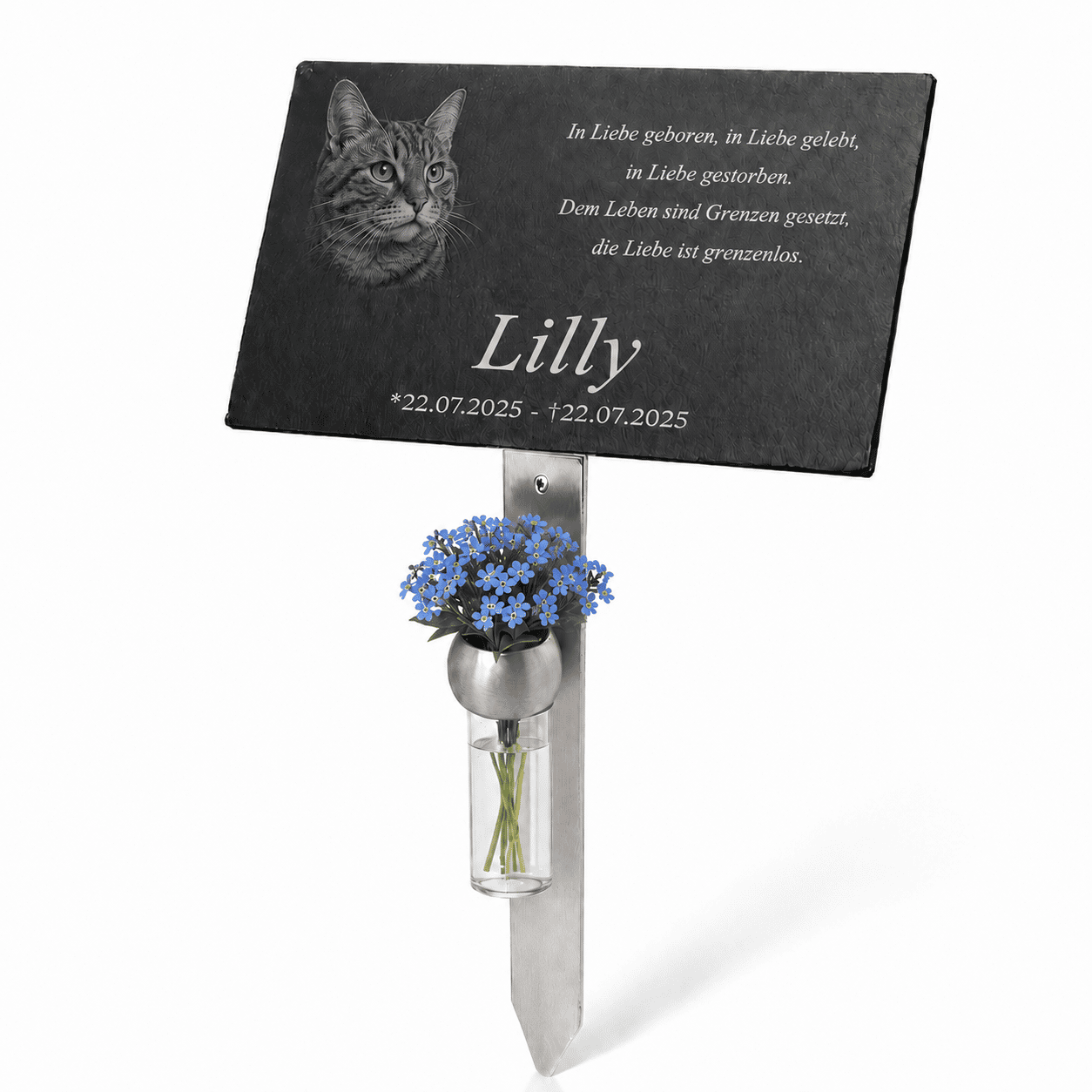 Personalisierte Gedenktafel für eine Katze mit graviertem Katzenporträt, dem Namen ‚Lilly‘, vierzeiligem Trauerspruch und Datumsangabe. Die schwarze Tafel ist auf einem Metallstab befestigt und mit einer Vase voller blauer Vergissmeinnicht geschmückt.