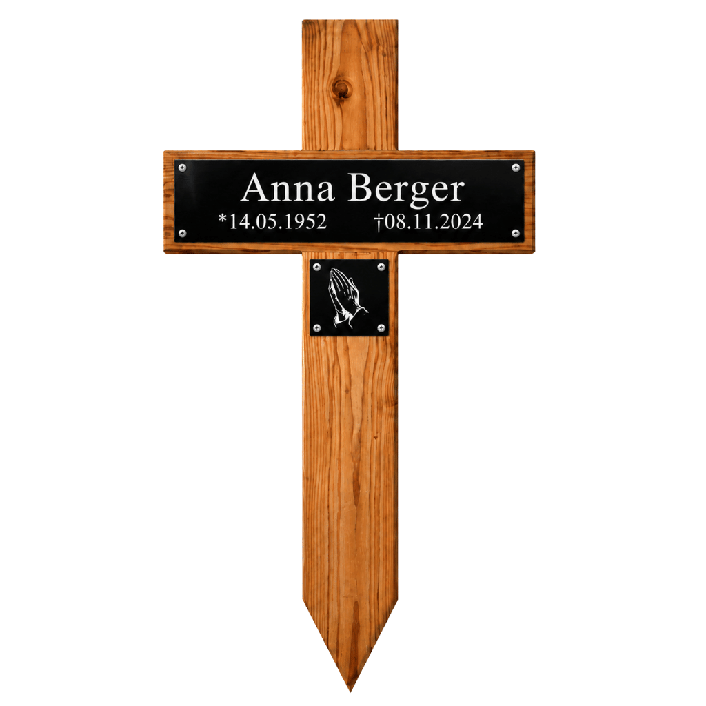 Holzkreuz mit spitz zulaufendem Fuß, schwarzem Namensschild „Anna Berger“, Geburtsdatum 14.05.1952, Sterbedatum 08.11.2024 und kleiner Plakette mit betenden Händen.