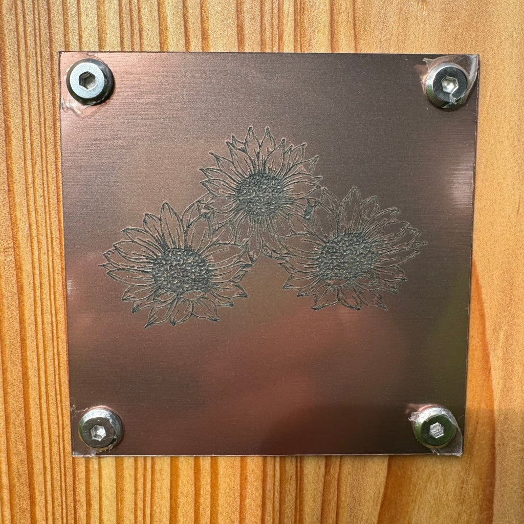 Graviertes Sonnenblumenmotiv auf bronzefarbenem Metallschild für ein personalisiertes Holzgrabkreuz