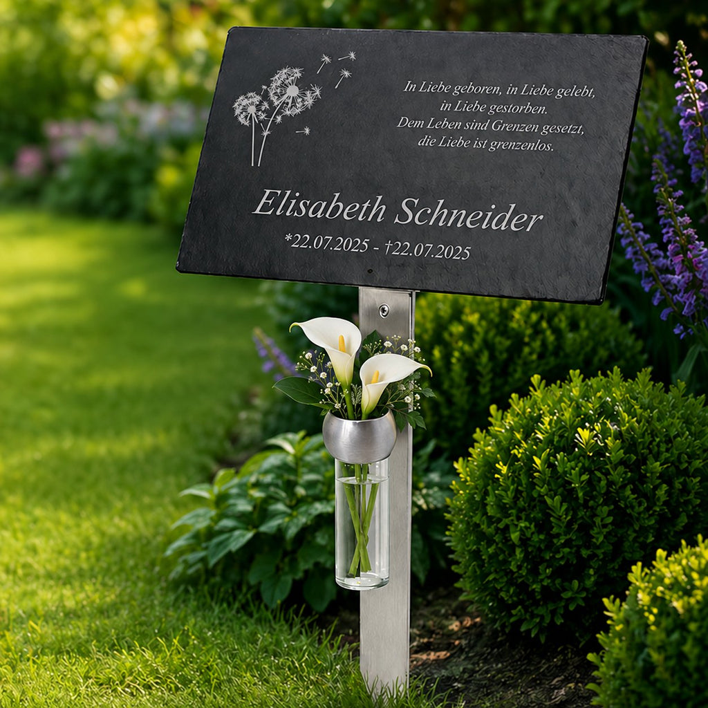 Personalisierte Schiefer-Gedenktafel für Elisabeth Schneider mit Pusteblumenmotiv und weißen Calla-Lilien in einer Glasvase.