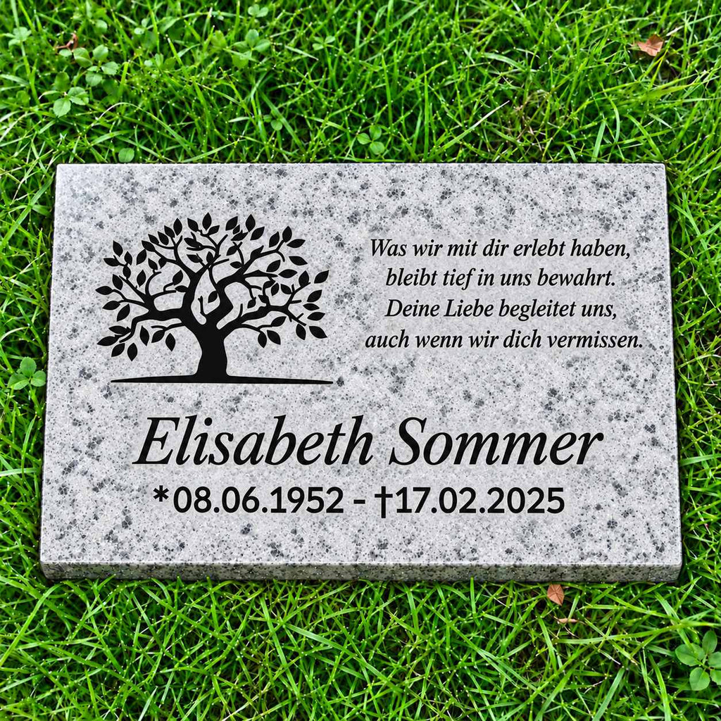 Personalisierte Granit-Gedenktafel Padang Cristallo mit schwarzem Lebensbaum, Name, Datum und Gedicht auf grünem Rasen.