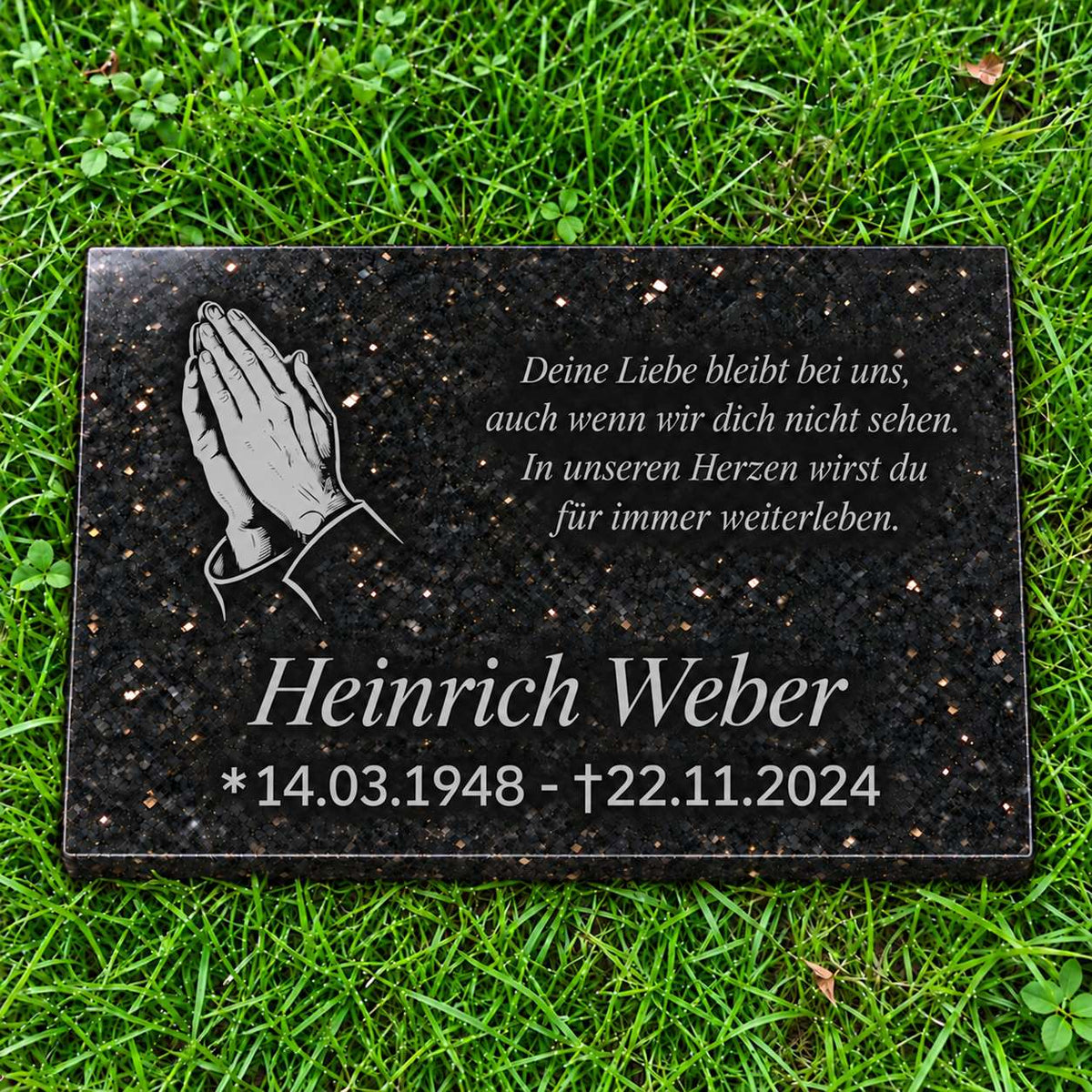 Schwarze Granit-Gedenktafel Star Galaxy mit hellgrauen betenden Händen sowie Name, Datum und Gedicht in Hellgrau auf grünem Rasen.