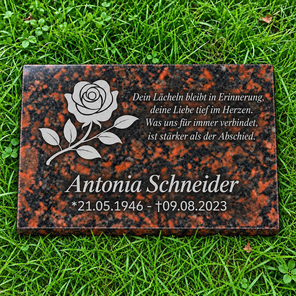 Rotbraune Granit-Gedenktafel Tan Brown mit hellgrauer Rose sowie Name, Datum und Gedicht in Hellgrau auf grünem Rasen.