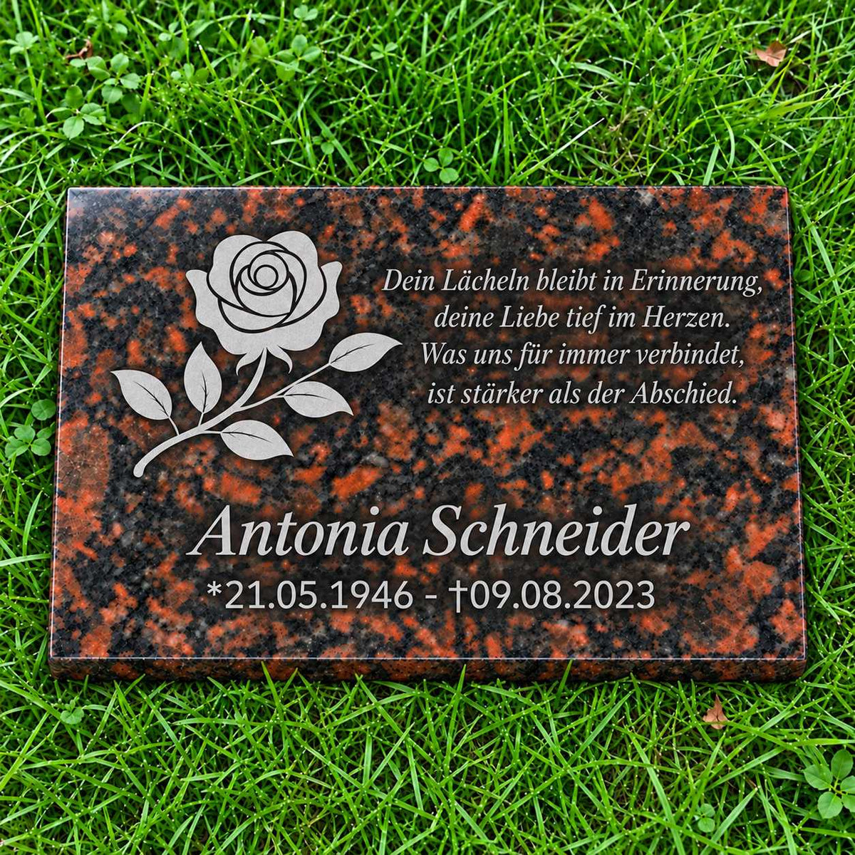 Rotbraune Granit-Gedenktafel Tan Brown mit hellgrauer Rose sowie Name, Datum und Gedicht in Hellgrau auf grünem Rasen.