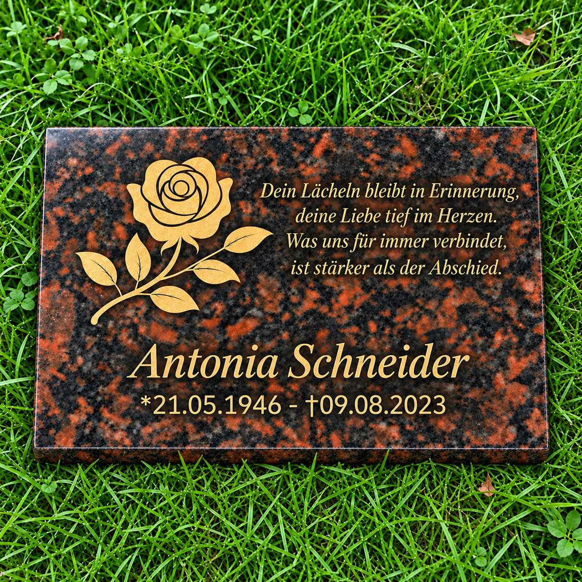 Rotbraune Granit-Gedenktafel Tan Brown mit goldener Rose, personalisiertem Namen, Datum und Gedicht auf grünem Rasen.
