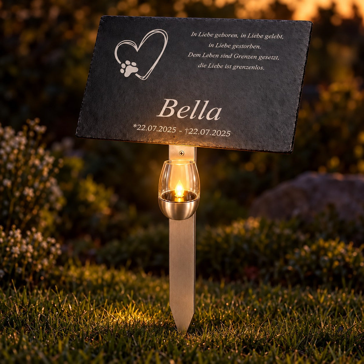 Personalisierte Tiergedenktafel aus Schiefer für Bella mit Herz-Pfoten-Motiv und warm leuchtendem LED-Gedenklicht am Edelstahlhalter.